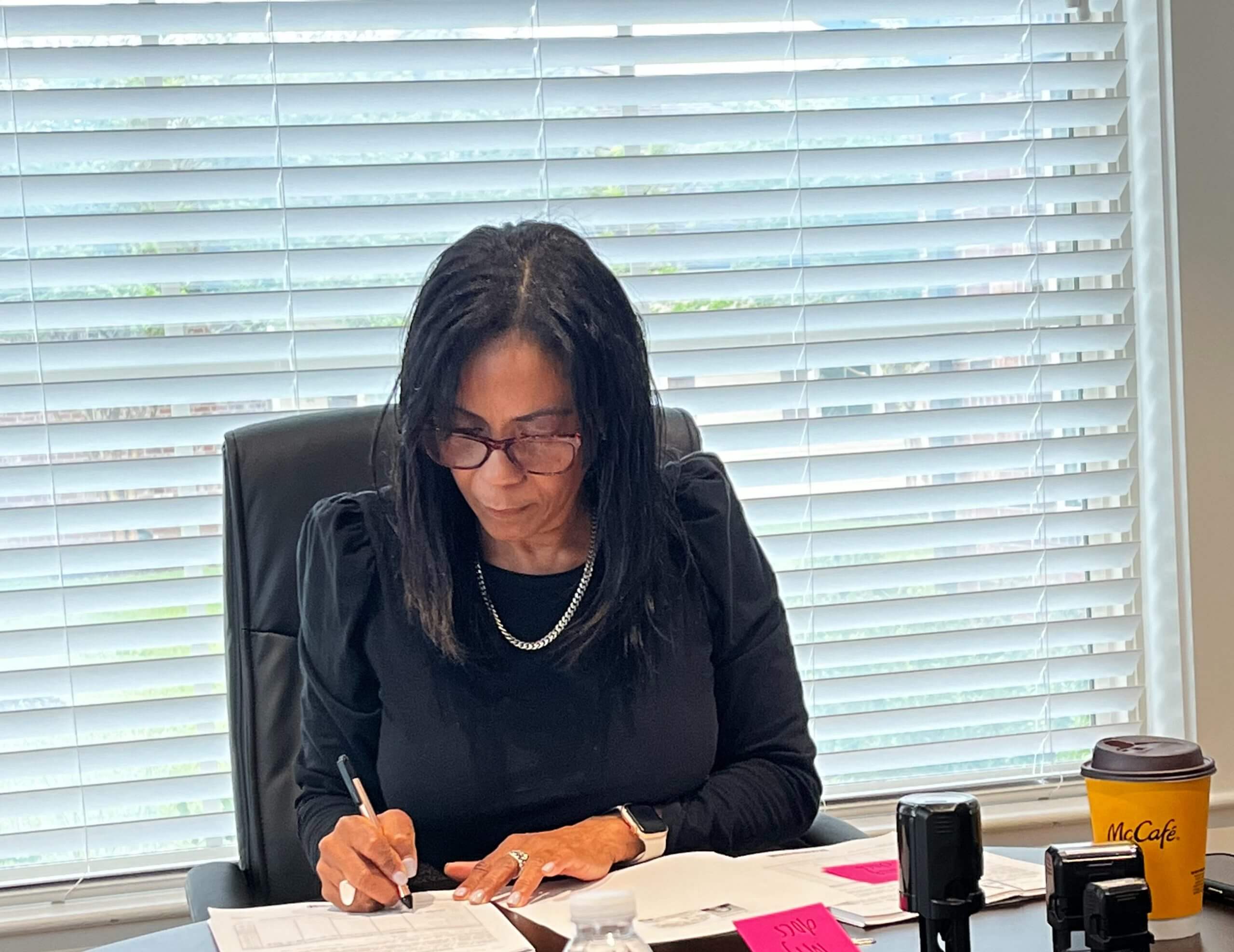 A woman sitting at her desk writing on paper.